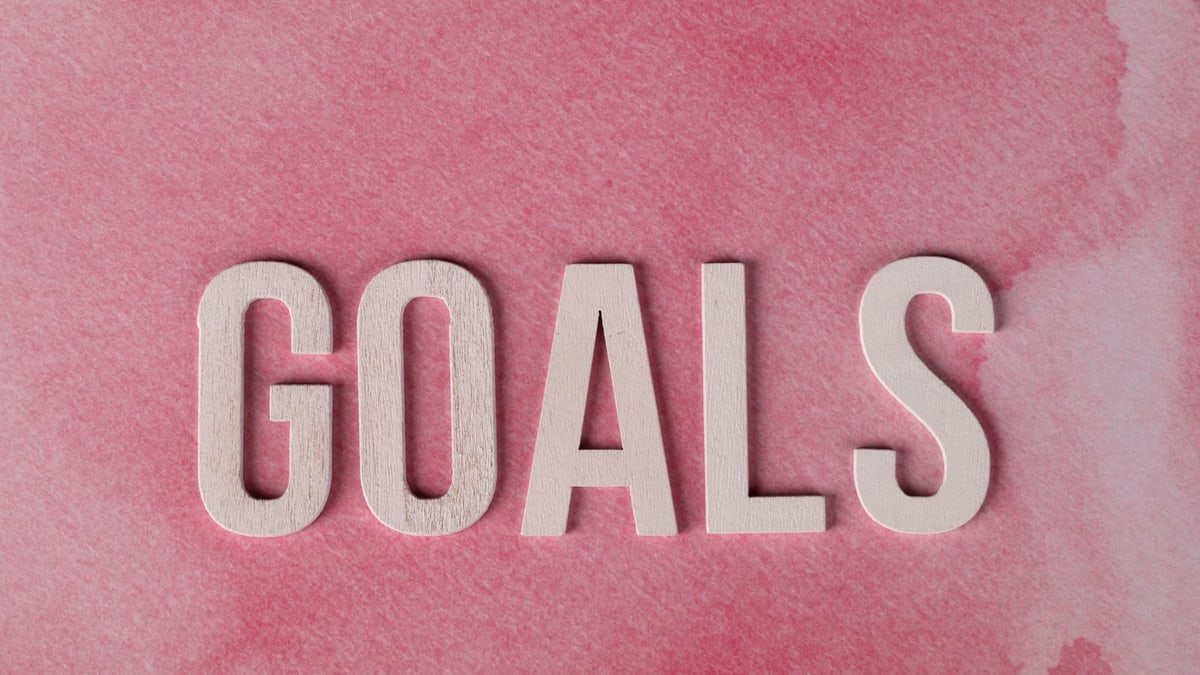 Motivational word 'GOALS' on a pink watercolor background for inspiration.